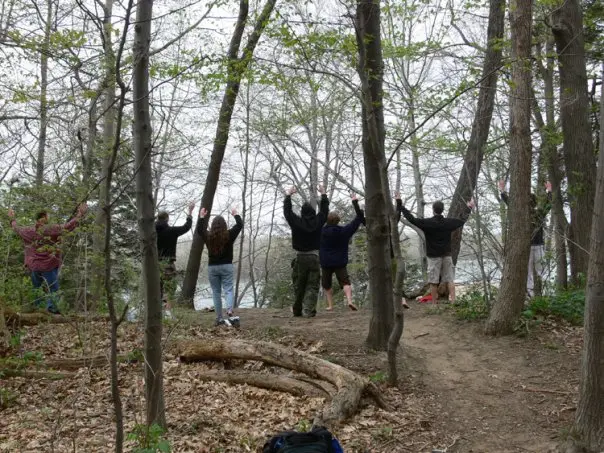 An outdoor group practicing Qigong near the water
