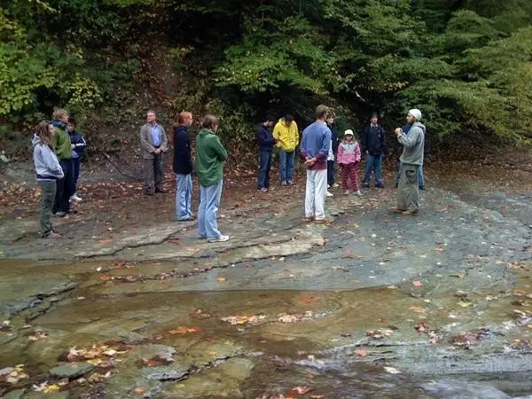 Dr. Micah Naziri leading an outdoor Hunyuan Qigong group beside a stream in Erie, Pennsylvania